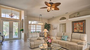 A spacious living room with a large sectional sofa, a glass coffee table, and a ceiling fan.