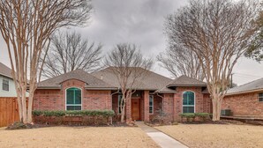 A brick house with a front yard, a wooden fence, and leafless trees. - Modern Carrollton Home - Private Pool & Grill (Carrollton)