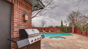 A backyard with a brick wall, a grill, a swimming pool, and a stone patio. - Modern Carrollton Home - Private Pool & Grill (Carrollton)