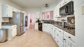 A spacious kitchen with white cabinets, stainless steel appliances, and a tiled backsplash. - Modern Carrollton Home - Private Pool & Grill (Carrollton)