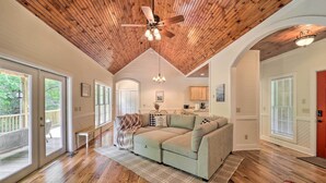 A spacious living room with a wooden ceiling, a beige sectional sofa, and a large window overlooking a deck. - Pond On-site! Dog-friendly Blue Ridge Mtn Retreat (Banner Elk)