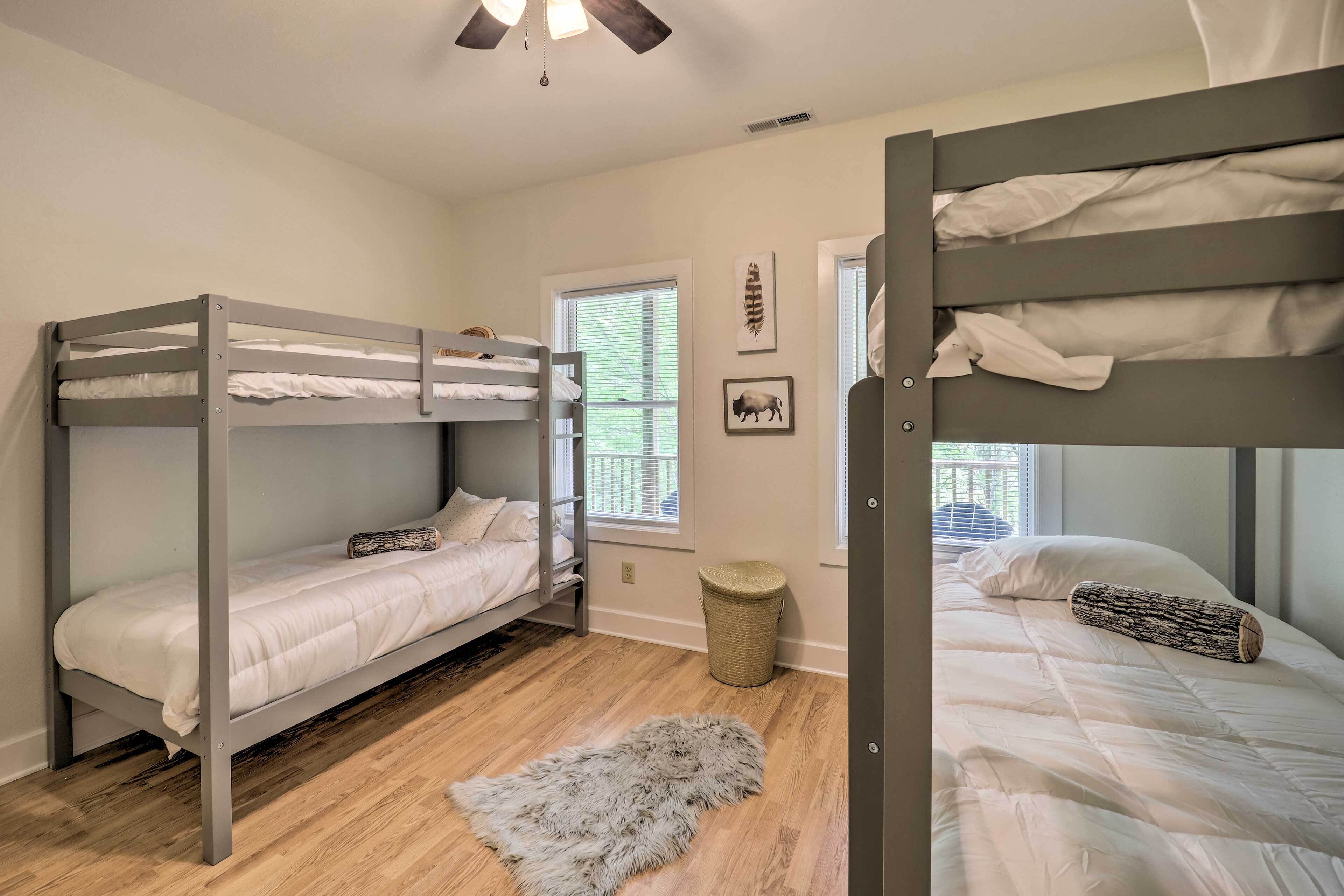 A dormitory room with bunk beds, a window with blinds, a woven basket, and a fur rug on the floor.