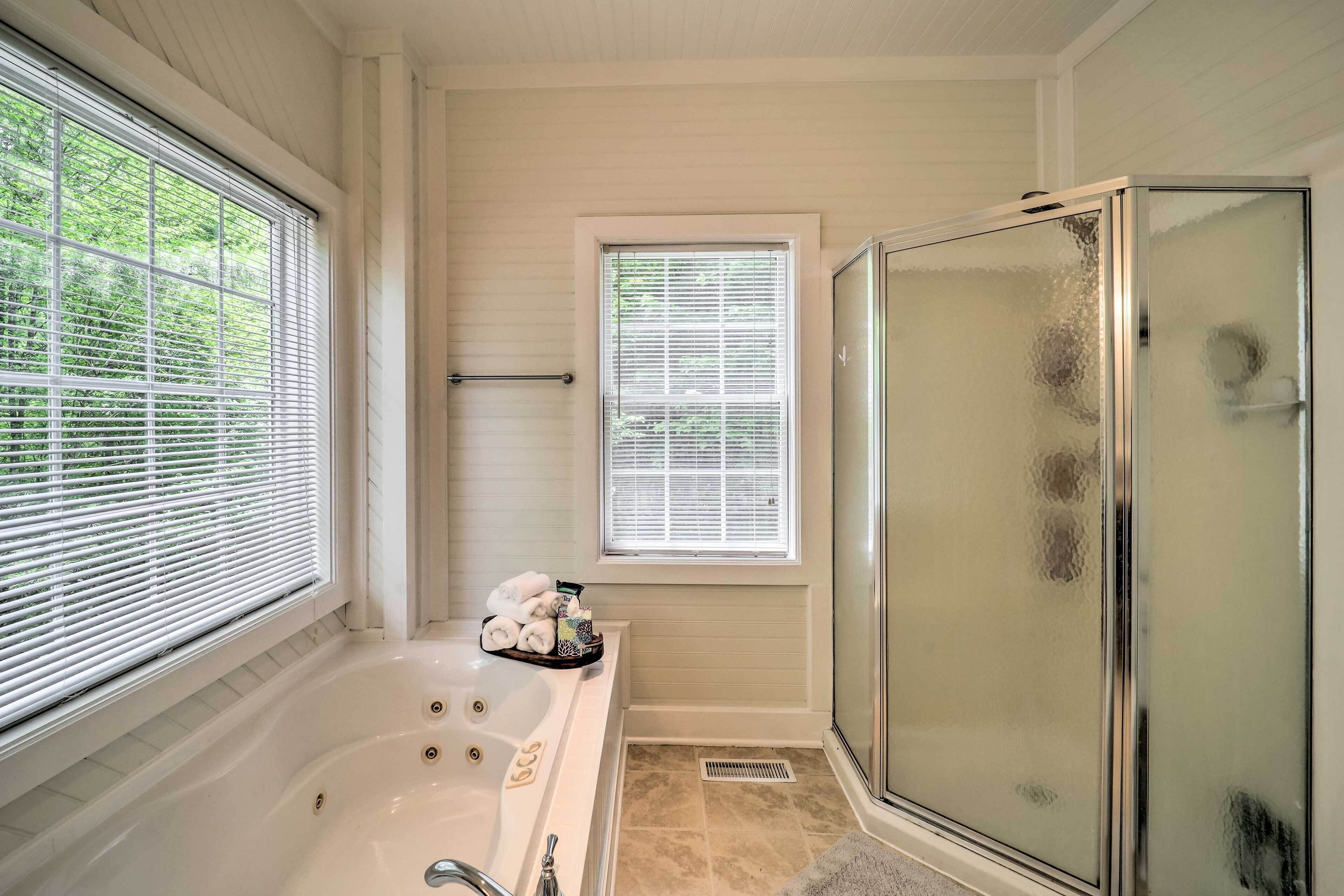 Une salle de bain avec une baignoire, une cabine de douche en verre et une fenêtre avec des stores.