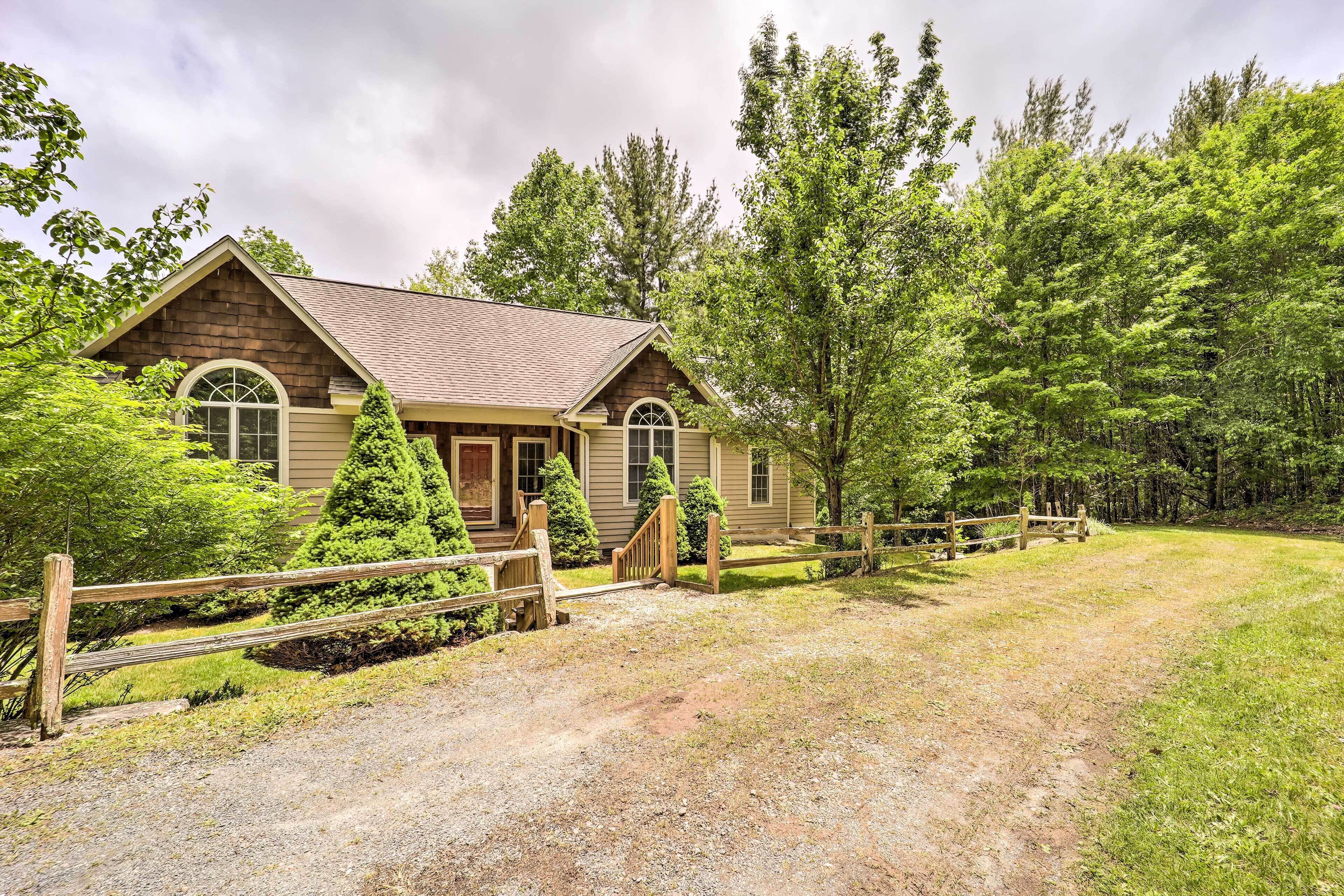 A rustic cabin with a gravel driveway and a wooden fence.