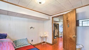 Een slaapkamer met een bed, nachtkastje, lamp en een houten deur naar een andere kamer.