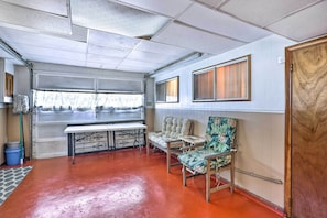 A room with a red floor, a bench, a table, and a door. - Pet-friendly Birmingham Apartment w/ Patio! (Birmingham)