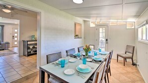 A dining area with a long table set for six, a kitchen area with a counter and shelves, and a separate seating area with a chair. - Private Desert Retreat w/ Grill & Mtn Views! (Phoenix)