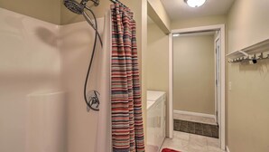 A bathroom with a shower, a white bathtub, and a striped shower curtain.