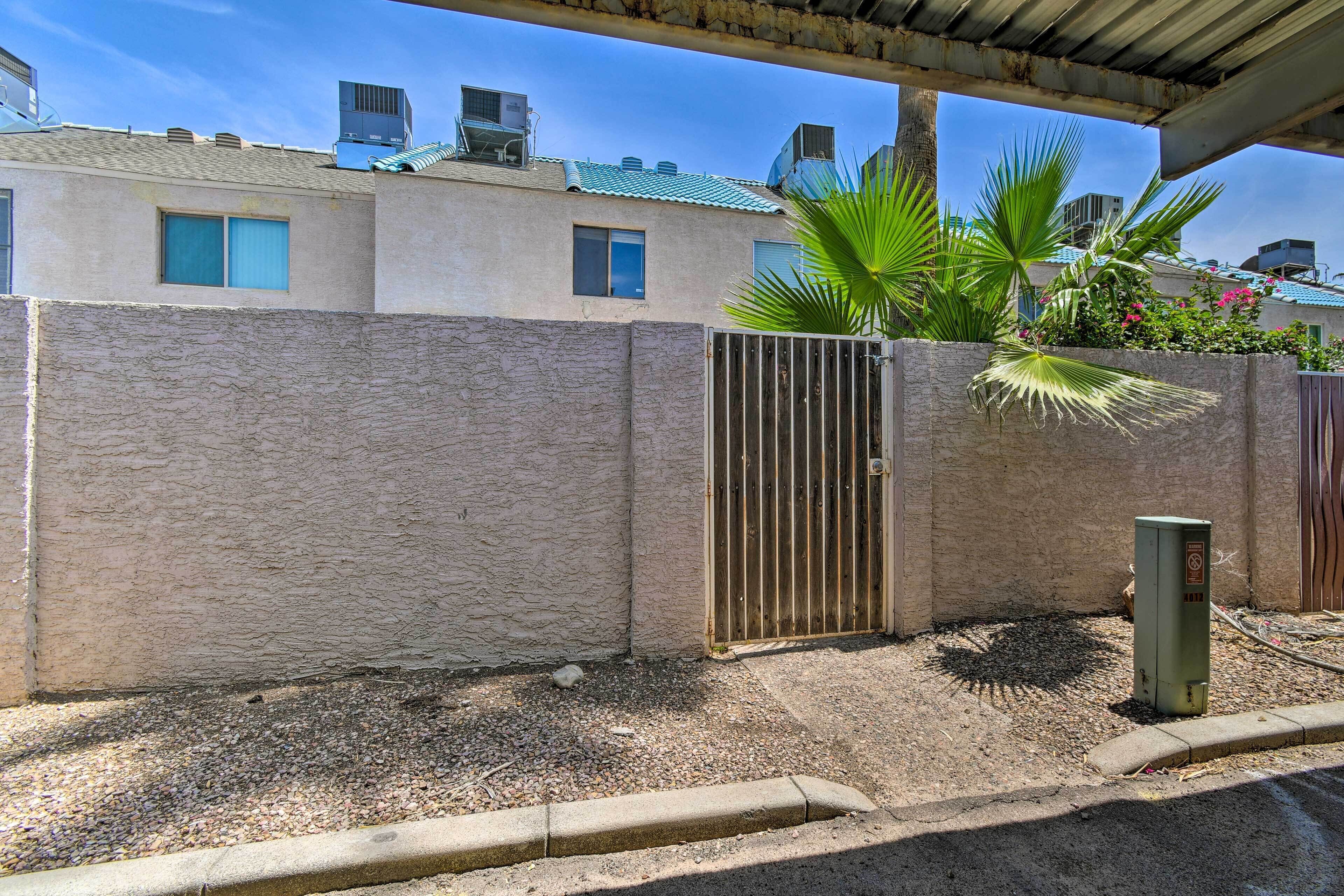 A residential area with a gated entrance, a palm tree, and a utility box.