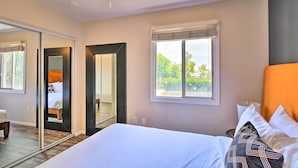 A bedroom with a large bed, a window with a view, a mirror, and a door leading to another room. - Scottsdale Townhome w/ Pool Access, Near Old Town! (Scottsdale)