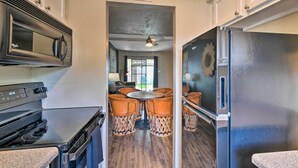 A compact kitchen with a microwave, stove, and refrigerator. There is a dining area with a table and chairs. - Scottsdale Townhome w/ Pool Access, Near Old Town! (Scottsdale)