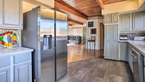 Une cuisine moderne dotée d’appareils électroménagers en acier inoxydable, de meubles de couleur gris clair et d’un plafond en bois.