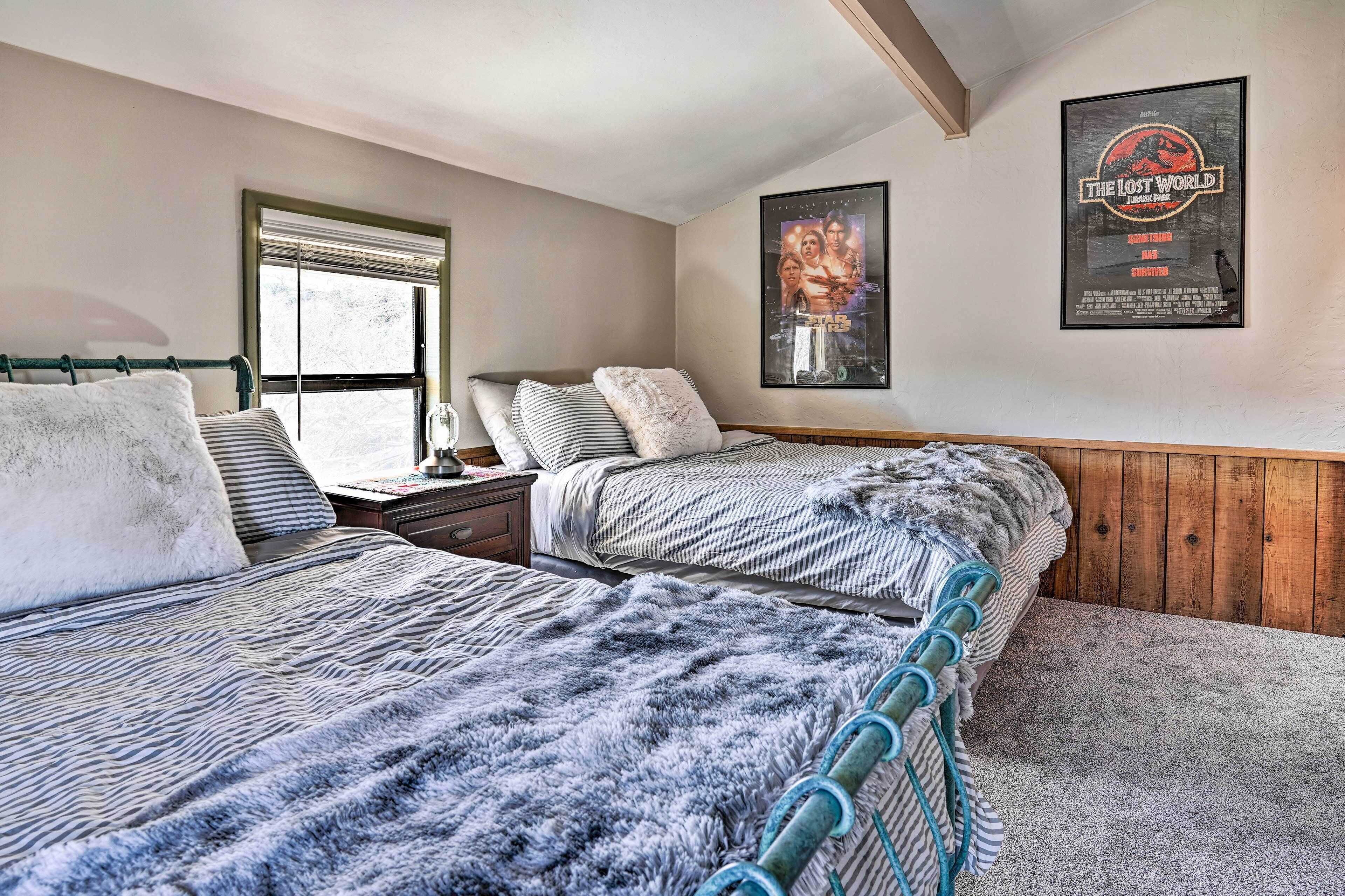 A bedroom with two beds, a window, a poster on the wall, and a wooden headboard.