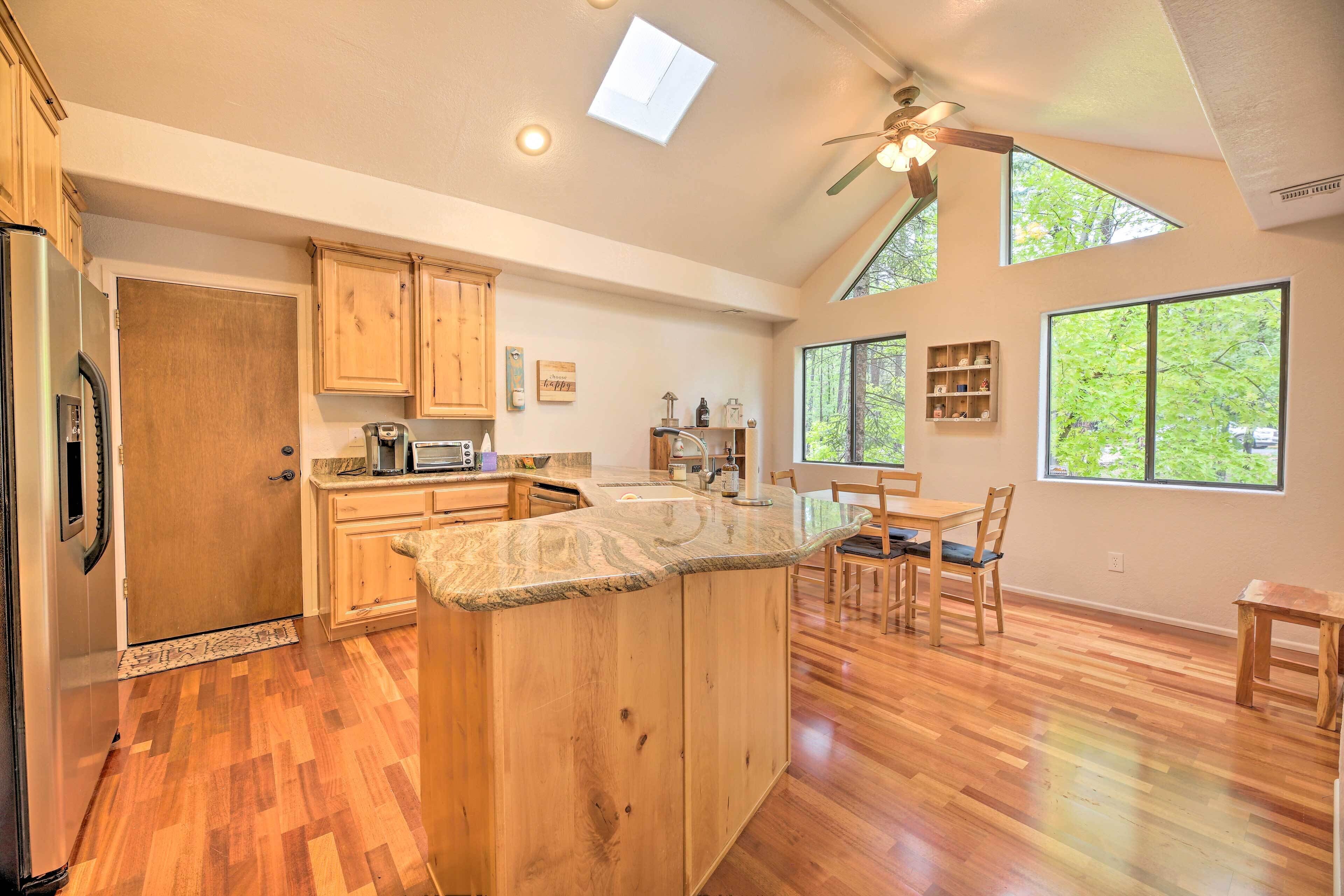 A spacious kitchen with wooden cabinets, a granite countertop, and a dining area with a table and chairs.