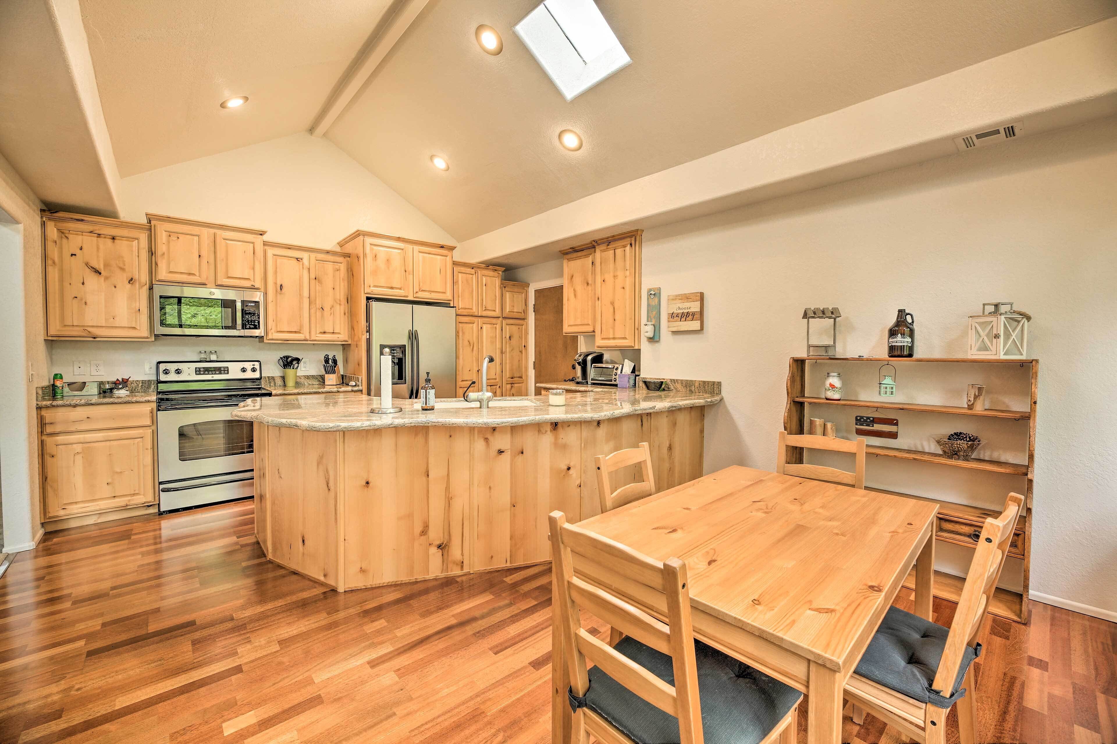 A kitchen with wooden cabinets, a central island, and a dining area with a table and chairs.