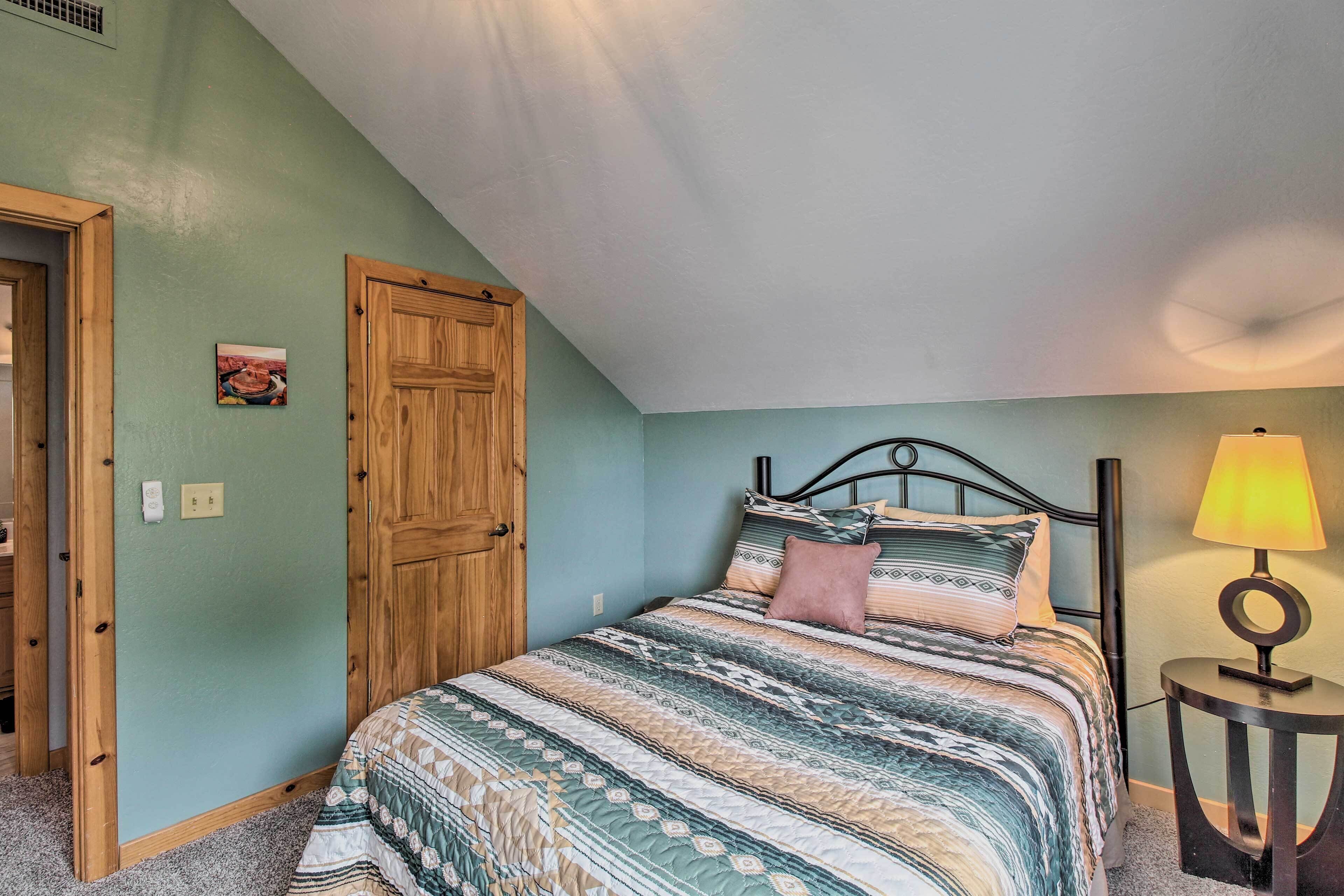 A bedroom with a bed, wooden door, and a lamp on a side table.