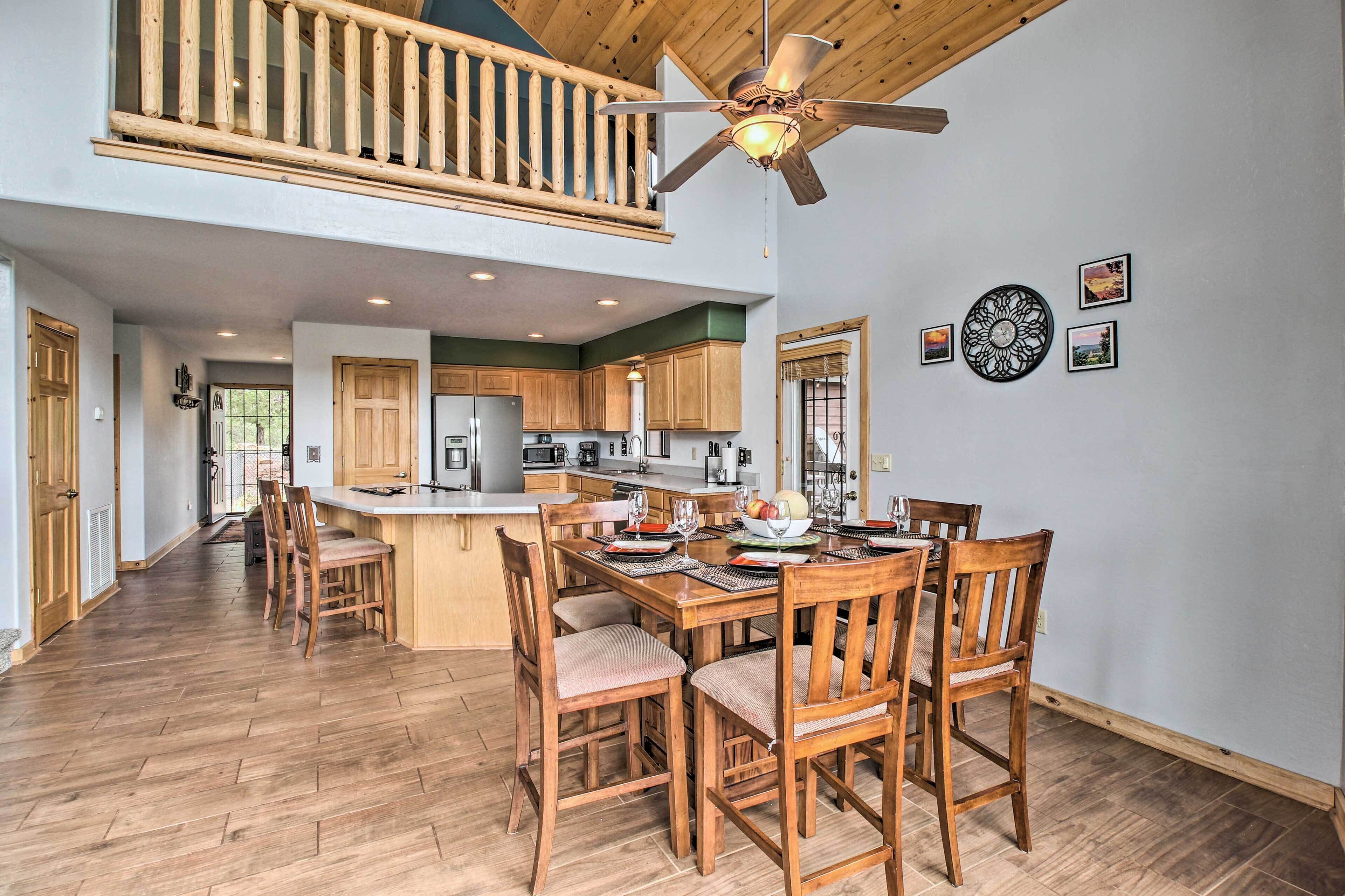 A spacious kitchen with wooden cabinets, a dining area with a large table and chairs, and a ceiling fan.