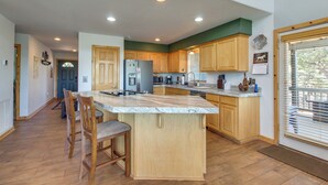 A spacious kitchen with wooden cabinets, a large island, and a view of the outdoors through a window. - Secluded Show Low Home Near Hiking Trails! (Show Low)
