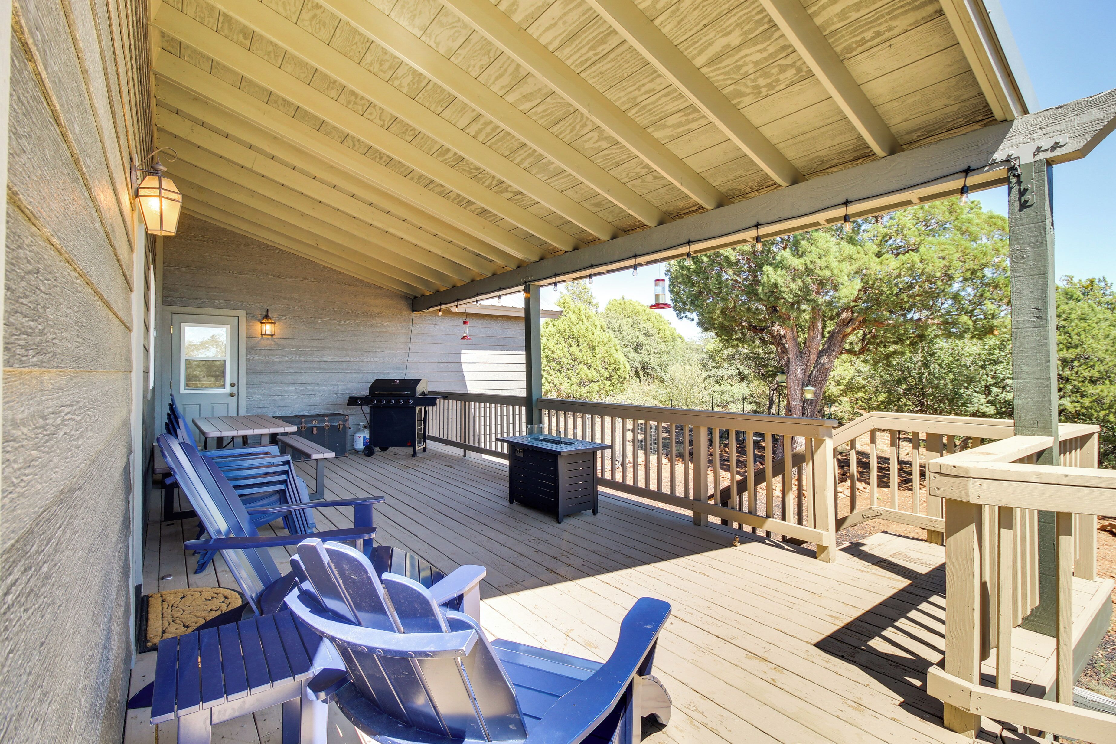 Una terraza techada con mobiliario exterior, una parrilla y un bote de basura.