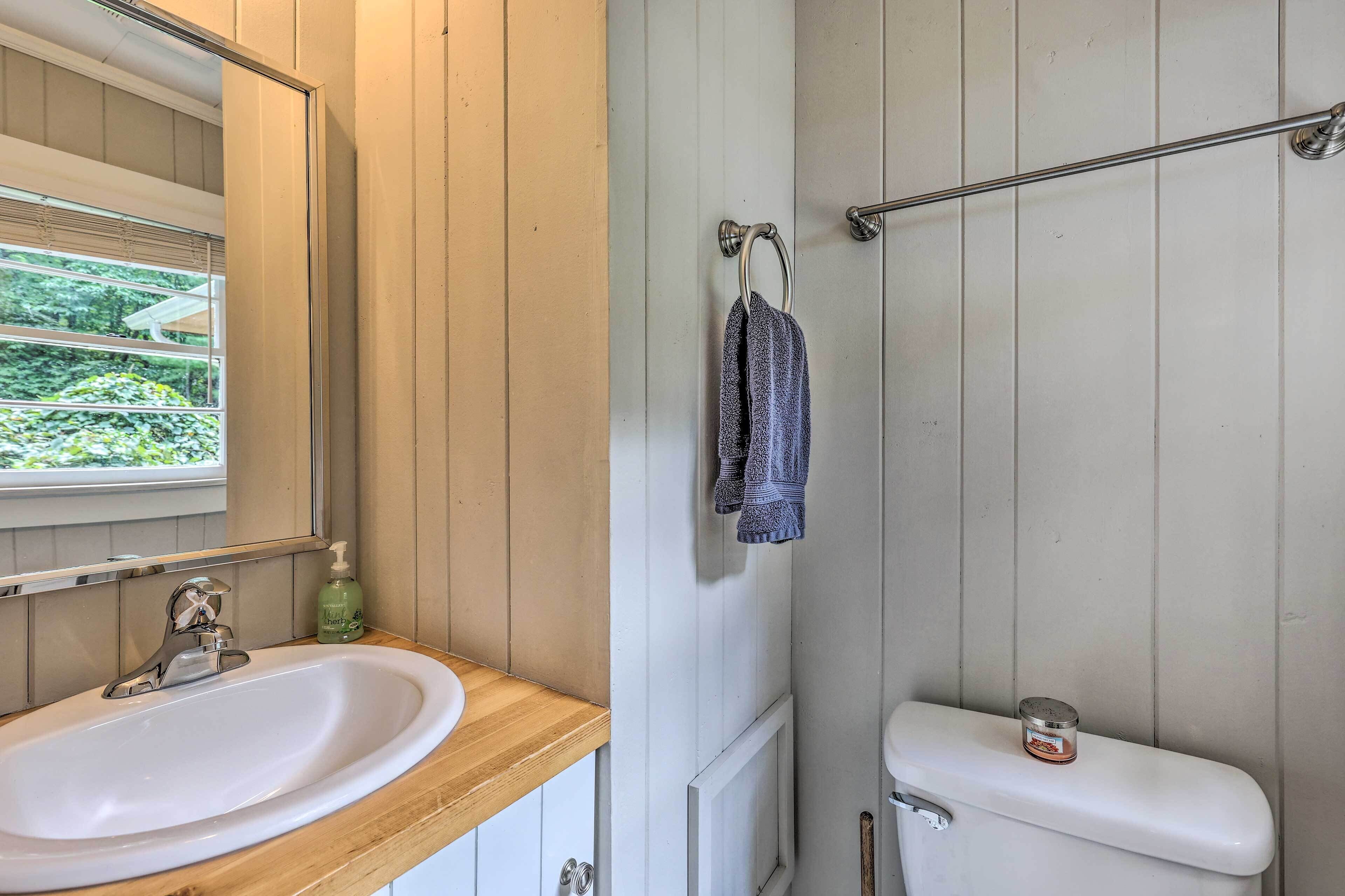 Un bagno con un mobile lavabo in legno, un lavandino, uno specchio, un portasciugamani e un water.