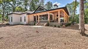 A two-story house with a covered porch and a brick fireplace. - All-encompassing Lakehouse w/ Modern Accents! (Edgemont)