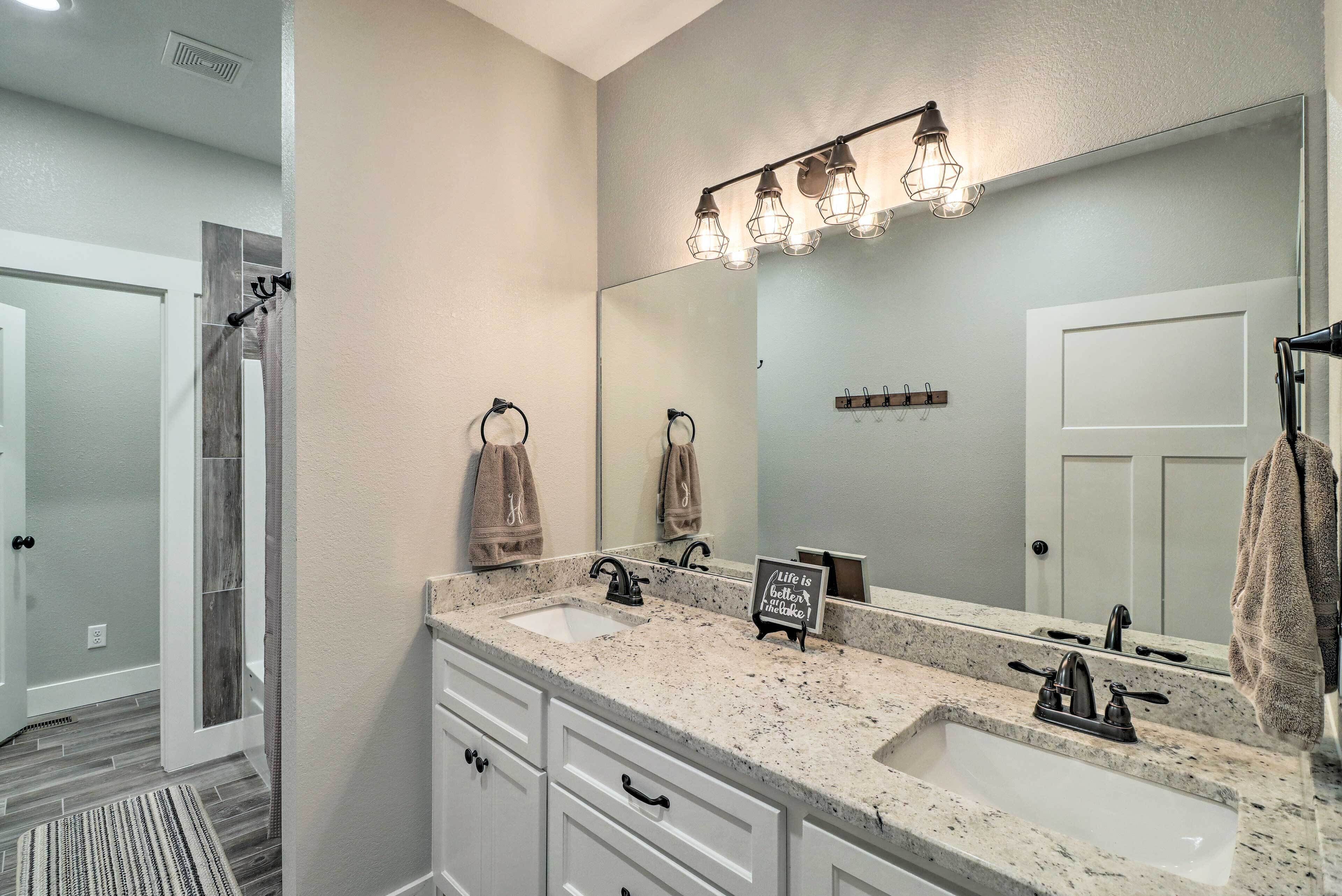 A bathroom with two sinks, a large mirror, and a towel rack.