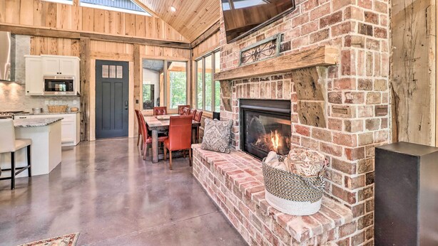 A spacious kitchen with a built-in microwave and a dining area with a red chair and a table. - All-encompassing Lakehouse w/ Modern Accents! (Edgemont)
