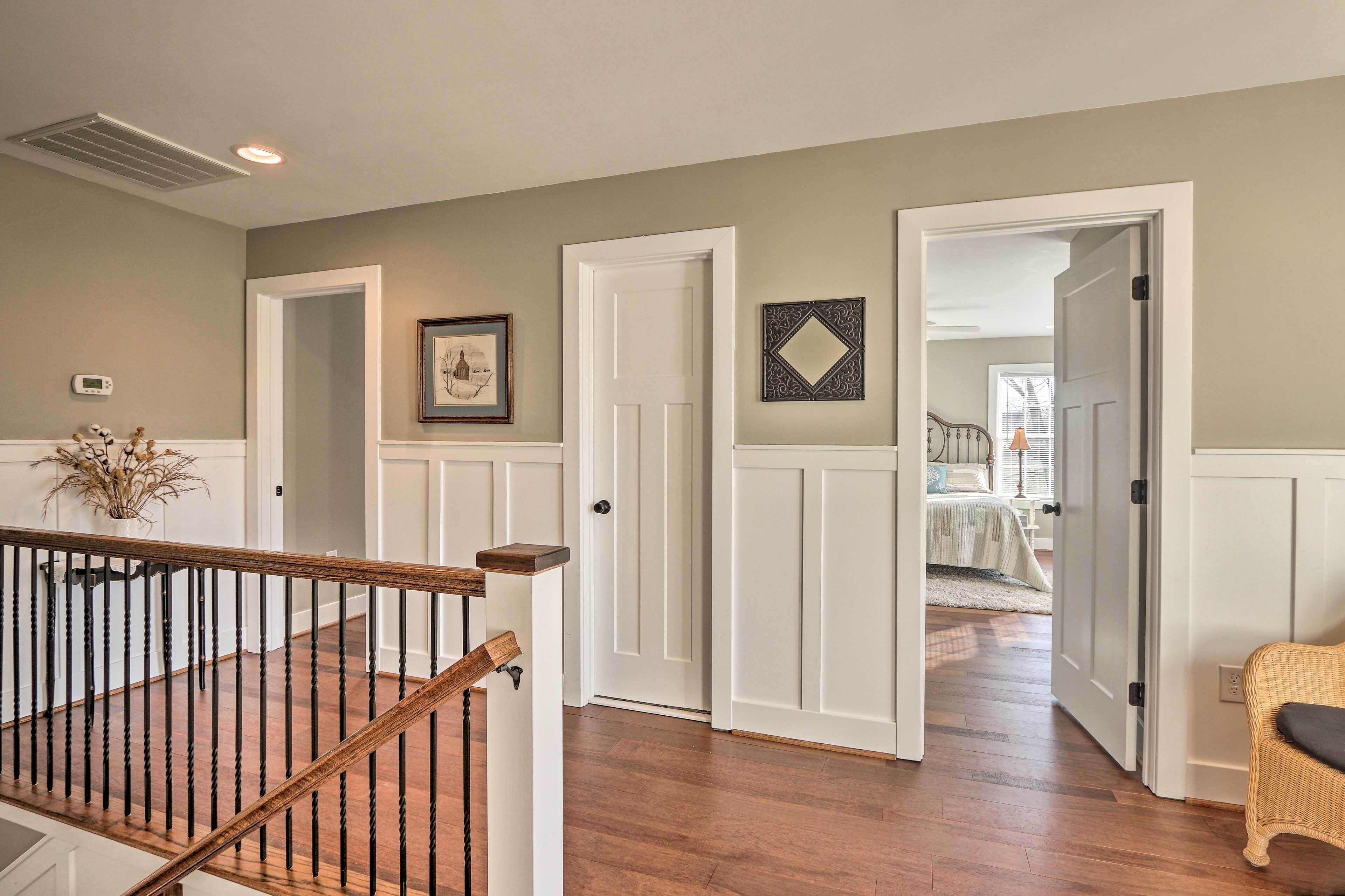 A hallway with white doors, a staircase, and a wicker chair.