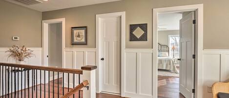 A hallway with white doors, a staircase, and a wicker chair.