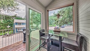 A balcony with a glass table and chairs, a grill, and a view of a house and trees. - Dreamy, Family-friendly Cloudcroft Townhome! (Cloudcroft)