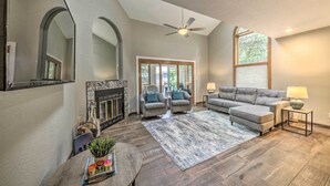 A spacious living room with a fireplace, grey sofas, a coffee table, and a large window. - Dreamy, Family-friendly Cloudcroft Townhome! (Cloudcroft)