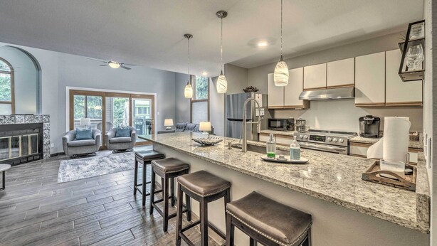 A modern kitchen with a large island, bar stools, and a dining area with a fireplace. - Dreamy, Family-friendly Cloudcroft Townhome! (Cloudcroft)