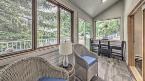 A covered porch with wicker chairs, a table, and a view of trees and a balcony. - Dreamy, Family-friendly Cloudcroft Townhome! (Cloudcroft)
