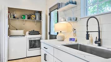 A modern kitchen with white cabinetry, a built-in oven, a dishwasher, and a large window providing natural light.