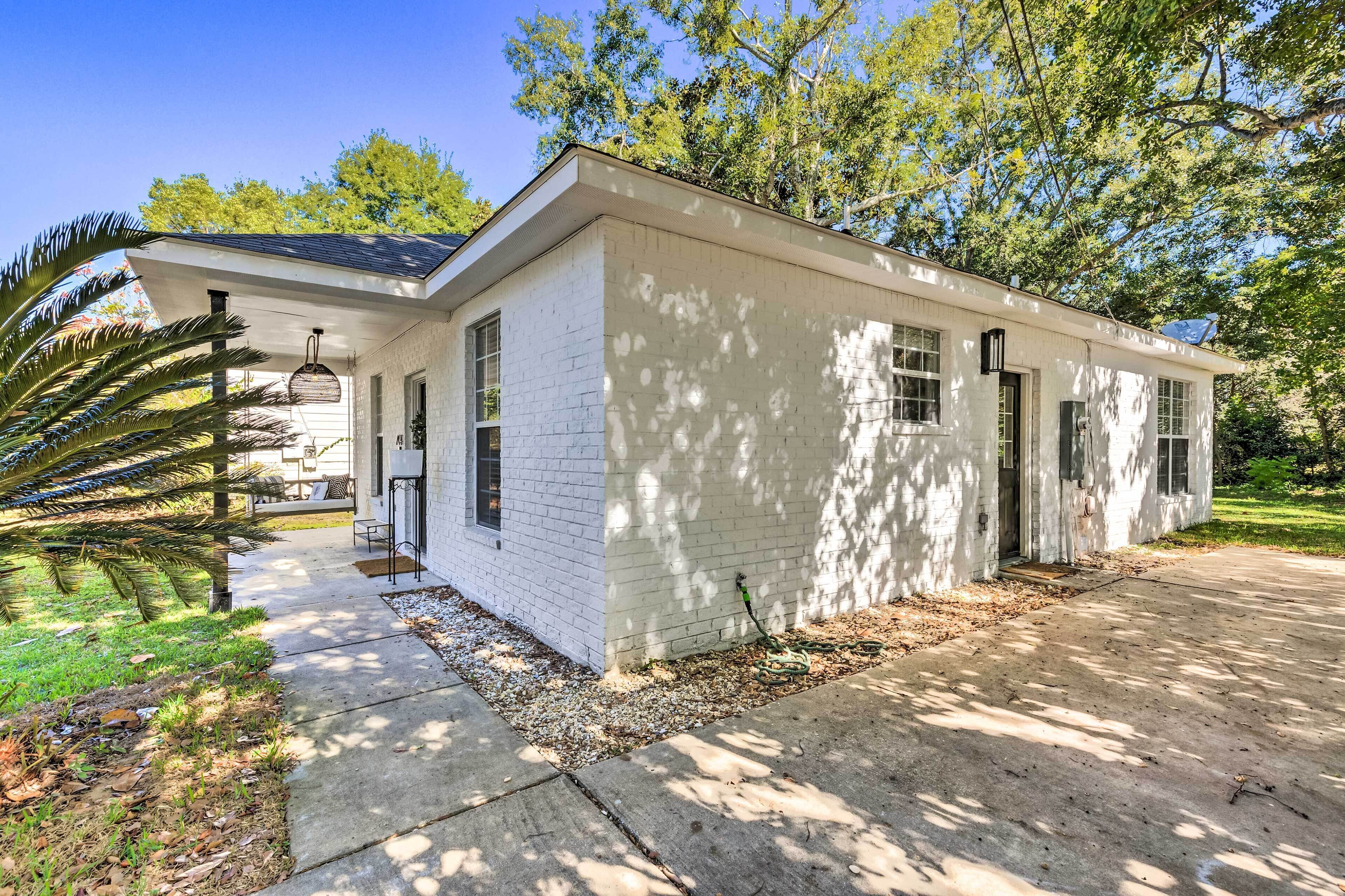 A single-story white house with a covered porch, a driveway, and a well-maintained lawn.