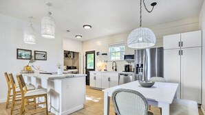 Een moderne keuken met witte kasten, een centraal eiland en hanglampen.
