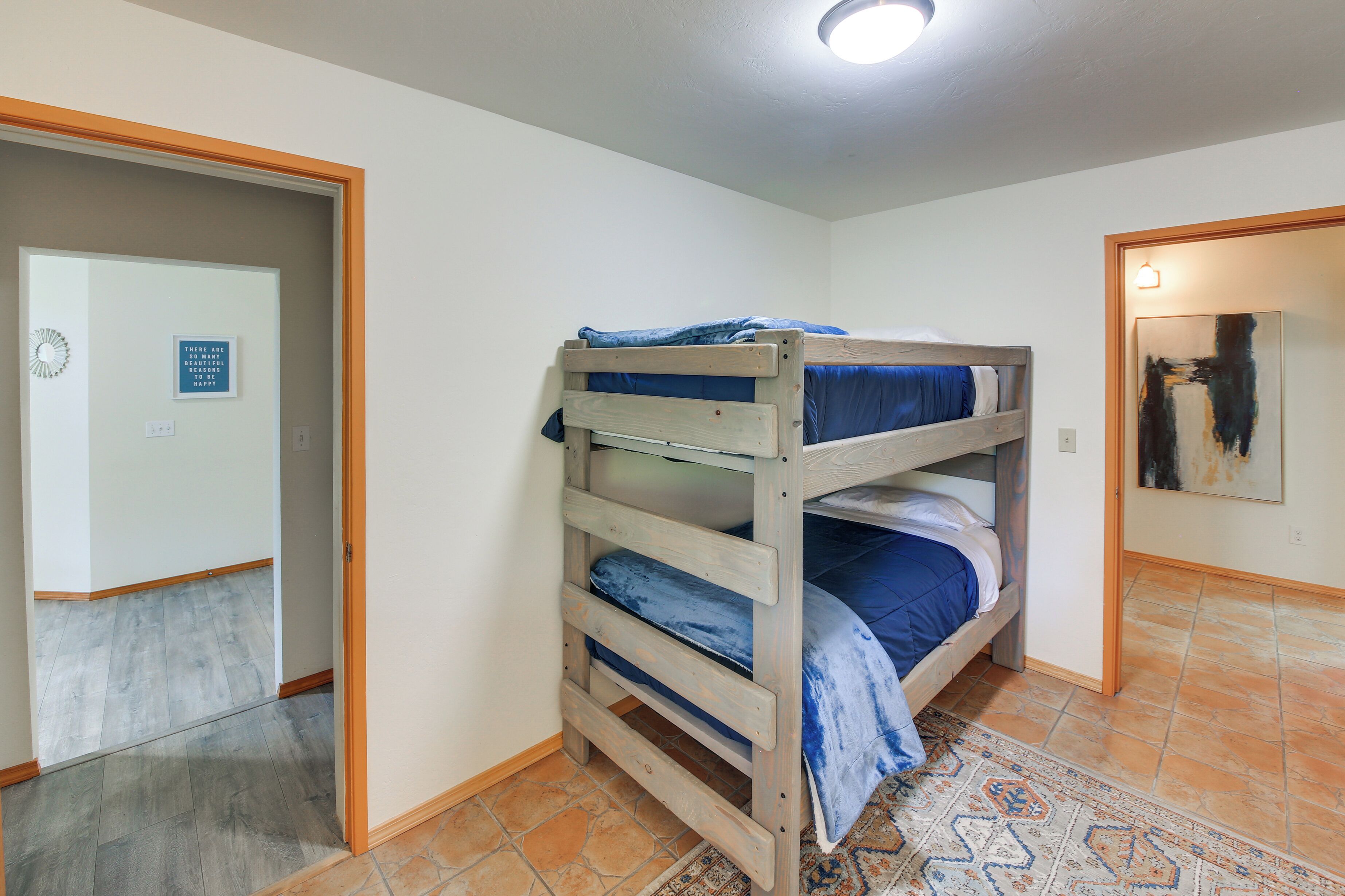 A room with a bunk bed, a patterned rug, and a door leading to another room.