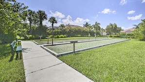 A park with a long, narrow rectangular lawn, several benches, and a pathway. - Sunny Ft Myers Abode w/ Community Amenities! (Fort Myers)