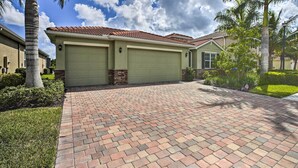A residential house with a brick driveway, green garage doors, and a tiled roof. - Sunny Ft Myers Abode w/ Community Amenities! (Fort Myers)