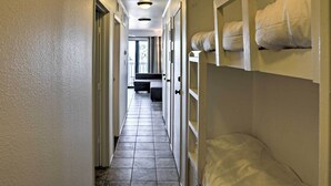 A hotel corridor with bunk beds on the right, a sofa in the background, and a tiled floor. - Surfside 'sandcastle Suite' w/ Balcony & 2 Pools! (Corpus Christi)