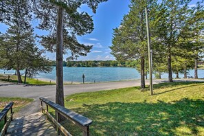 Een park aan het meer met een houten terras, bankjes en een pad naar het water.