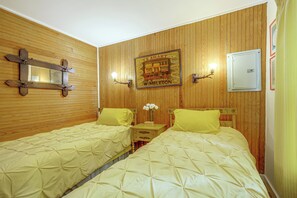 A room with two beds, wooden paneling, a mirror, wall-mounted light fixtures, and a framed picture. - Dainty New Preston Cottage w/ Dock & Lake Views! (New Preston)