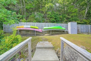 A wooden deck with a concrete ramp leading to a fenced area with kayaks. - Dainty New Preston Cottage w/ Dock & Lake Views! (New Preston)