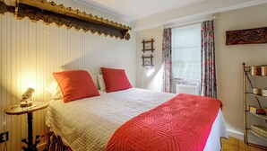 A bedroom with a bed, a bedside lamp, a window with curtains, and a wall-mounted shelf. - Dainty New Preston Cottage w/ Dock & Lake Views! (New Preston)