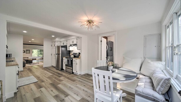 A modern kitchen with white cabinets, stainless steel appliances, and a dining area with a white sofa and table. - Bright & Airy Liberty Lake Abode w/ Backyard! (Liberty Lake)