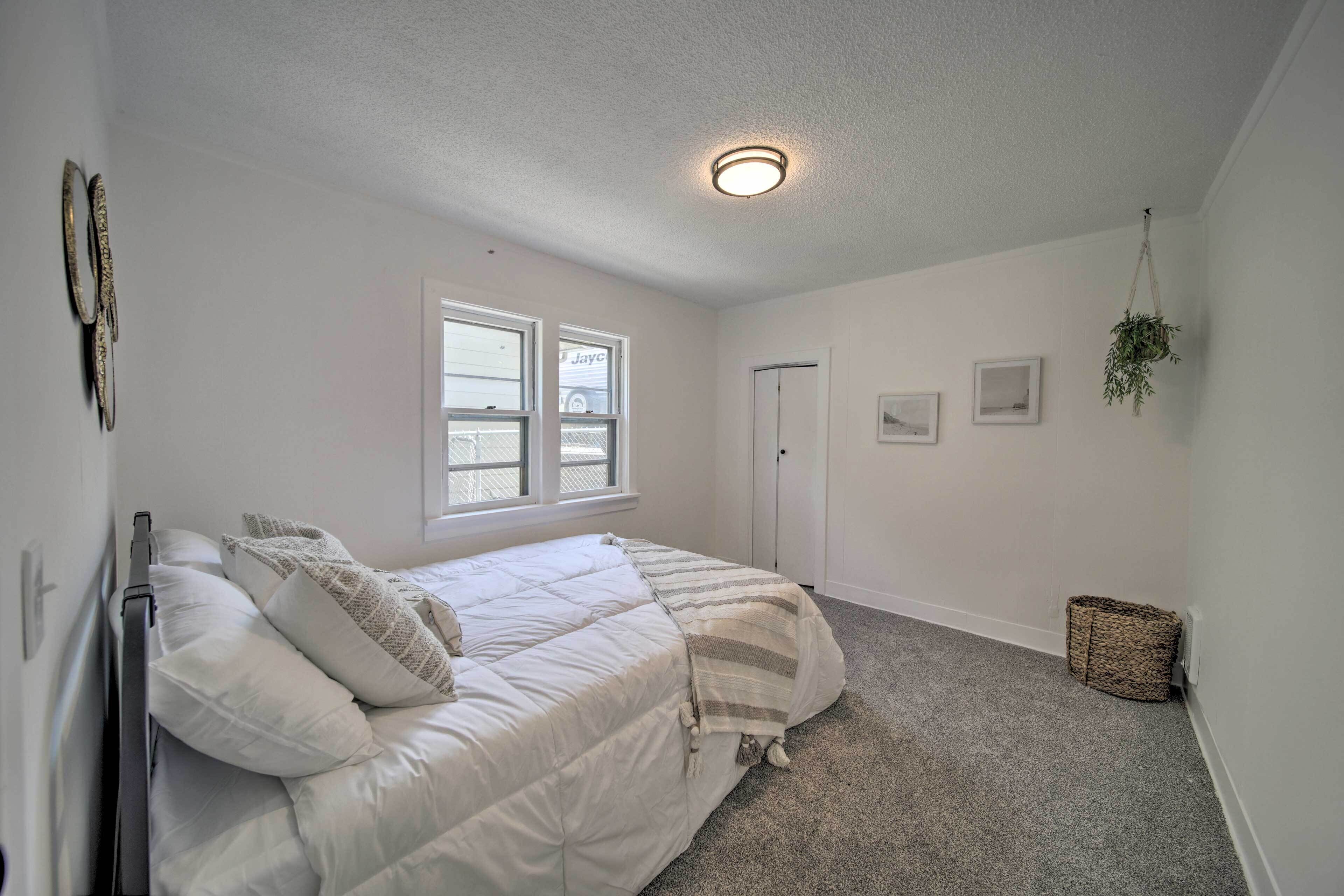 A bedroom with a bed, a window, a door, and a hanging plant. - Bright & Airy Liberty Lake Abode w/ Backyard! (Liberty Lake)