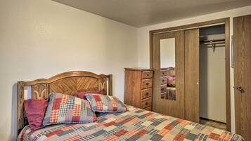 A bedroom with a wooden bed, a quilt, a wooden wardrobe, and a mirror.