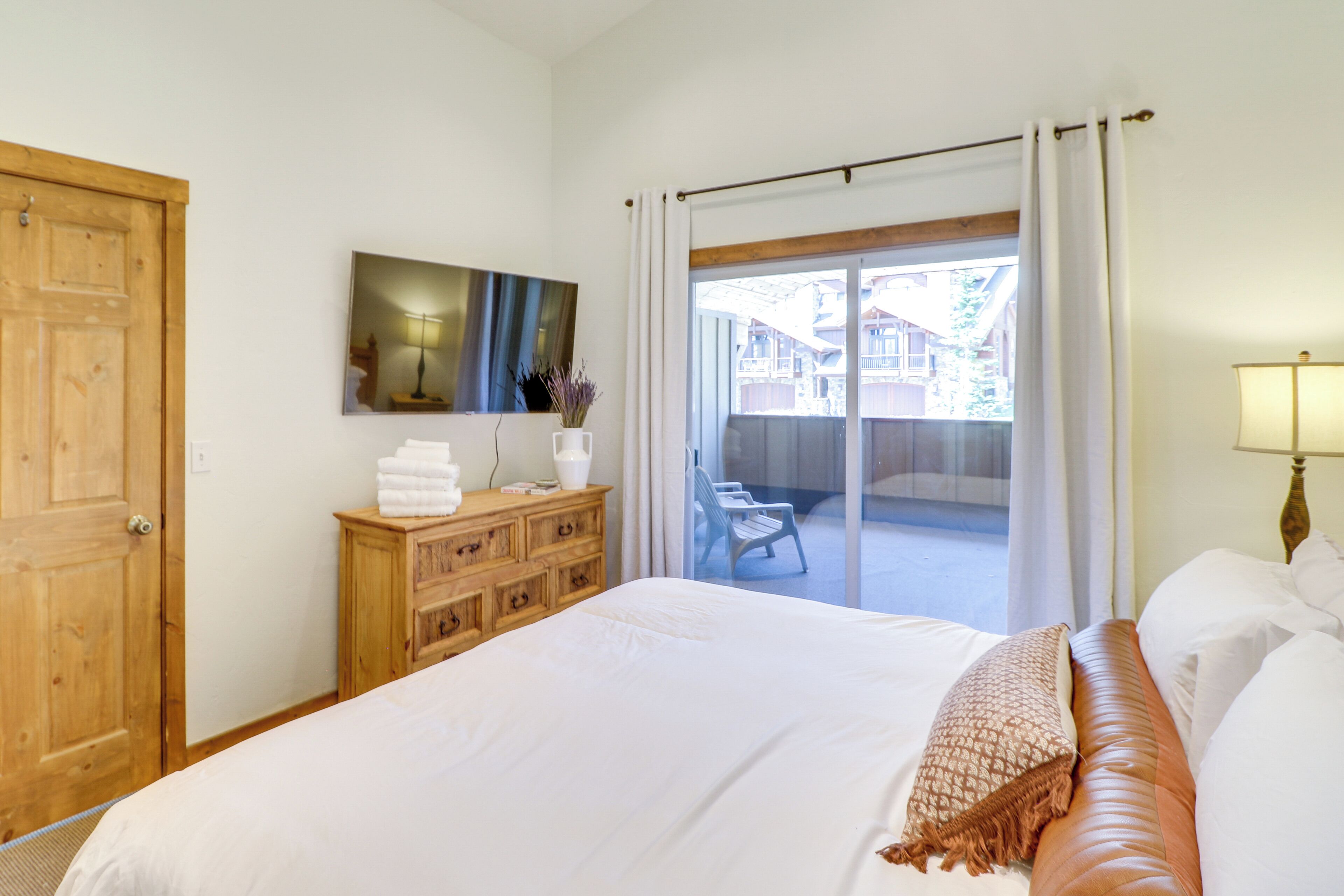 Ein Schlafzimmer mit einem großen Bett, einer Holzkommode und einem Balkon mit Sitzgelegenheiten.