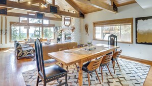 A spacious dining area with a large wooden table, several chairs, and a patterned rug.