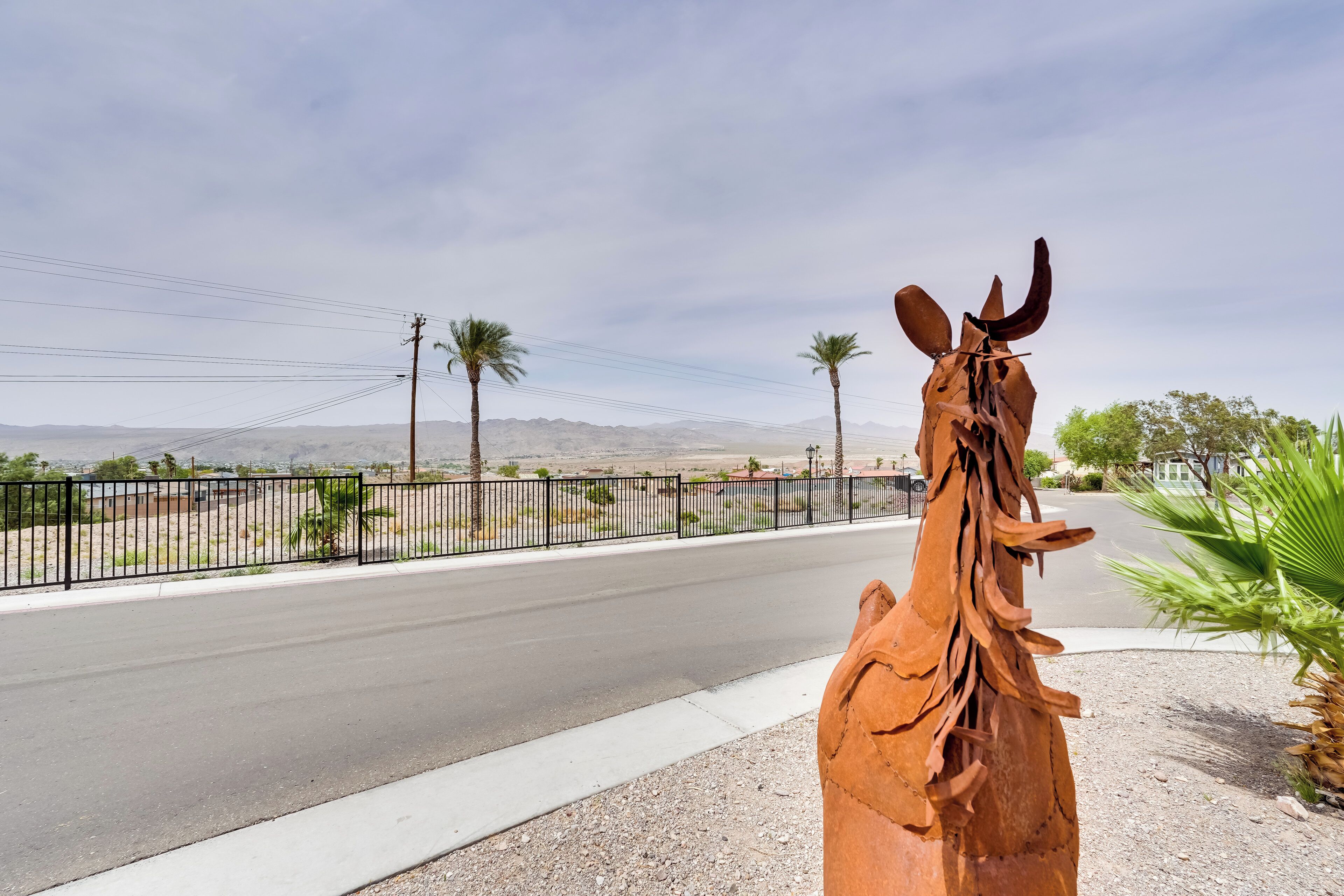 Une sculpture représentant la tête d’un cheval, placée sur un trottoir près d’une route.